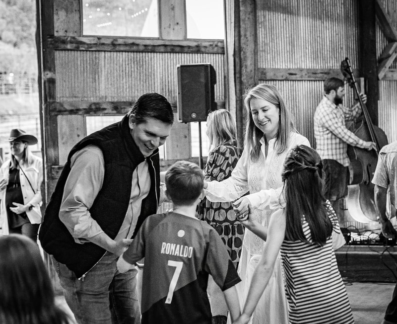 Black-and-white barn dance where a smiling man in a vest and a blonde woman in white dance in a linked circle.